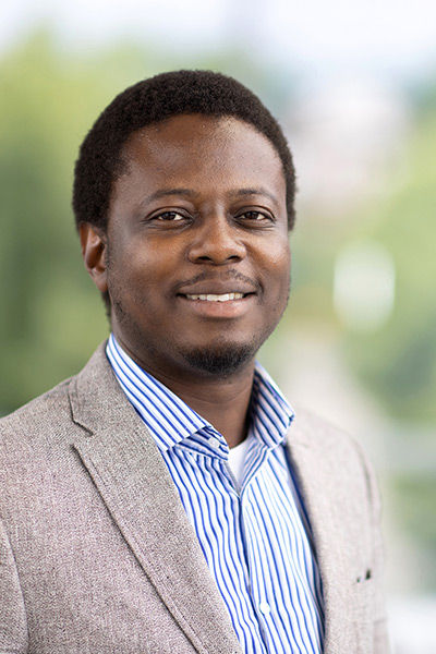 Adeniyi P. Asiyanbi stands in front of a blurry background