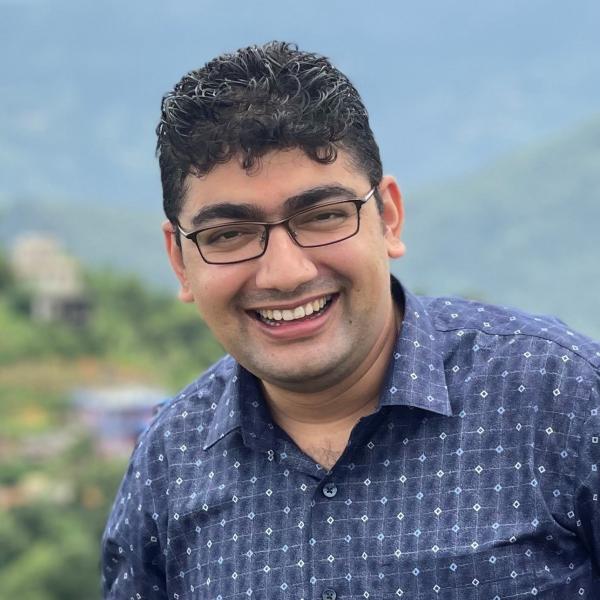 Kaushal Gnyawali smiles in front of blurry hills